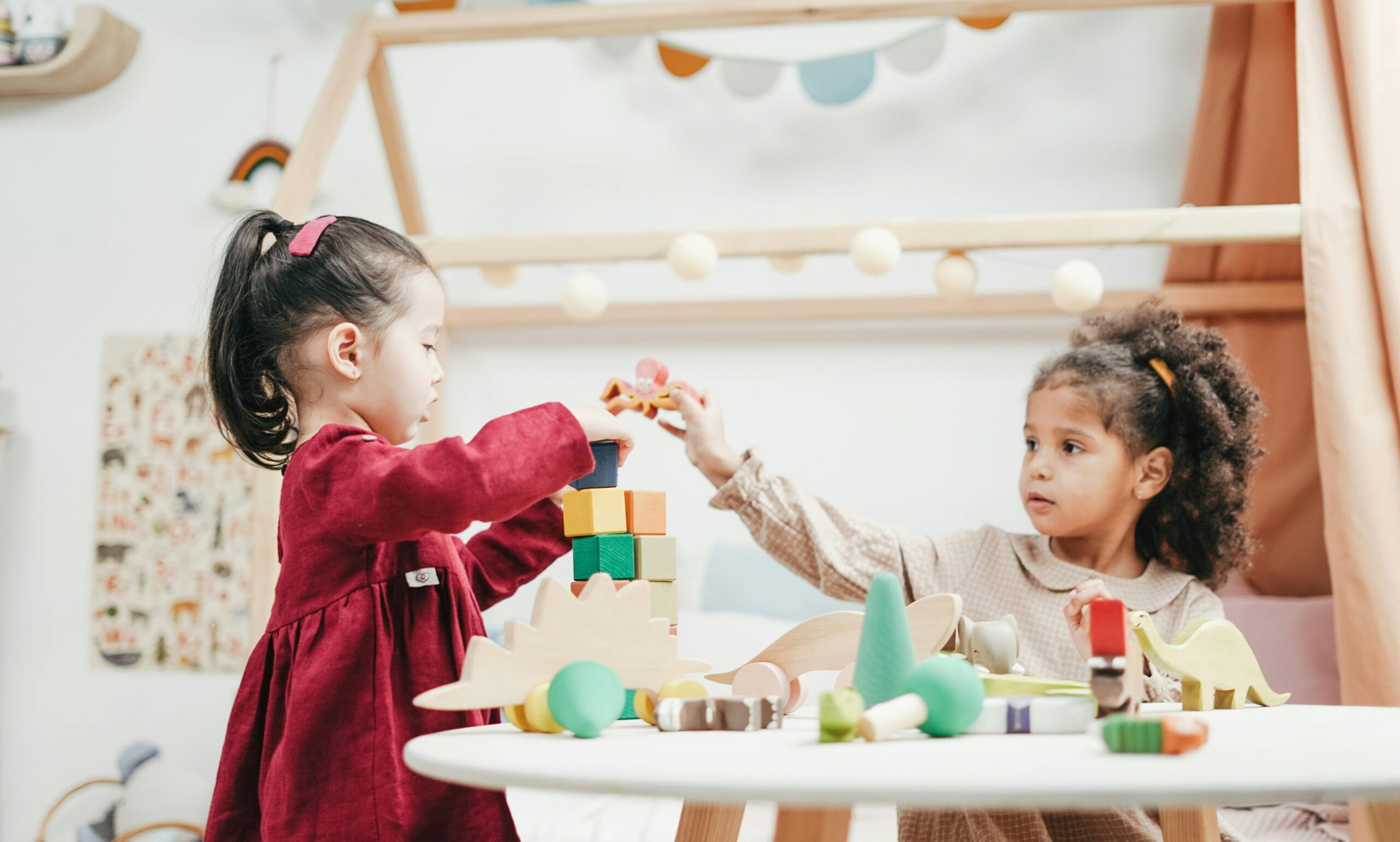 Two girls stacking blocks together.