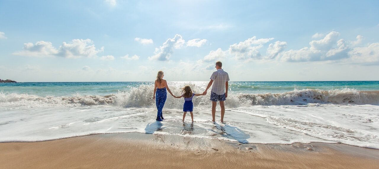 Family holding hands and playing together at the beach.