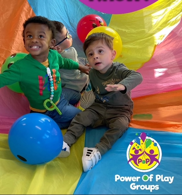 Three children playing on a parachute during a Power of Play Groups class.